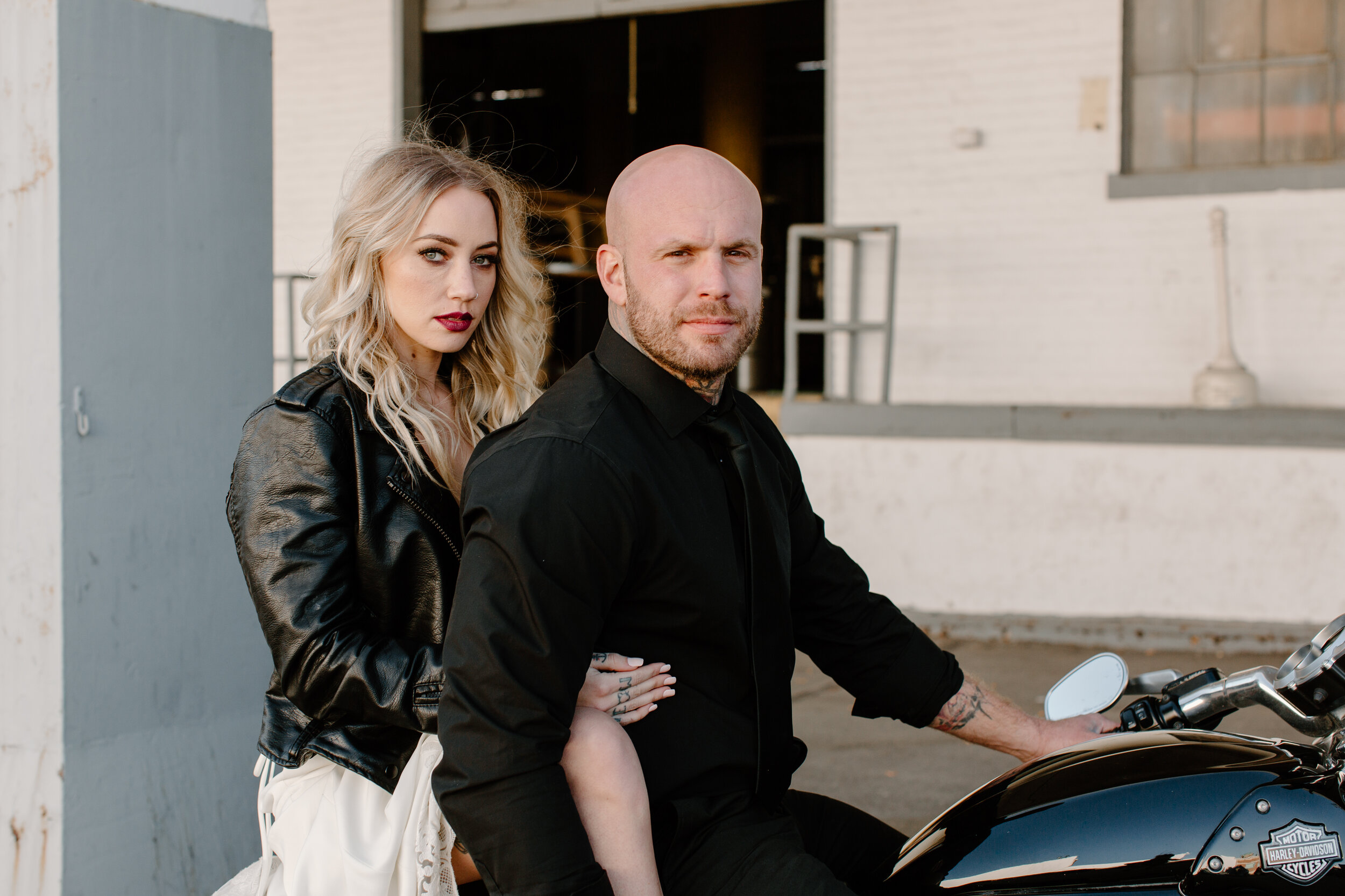 An edgy couple on their wedding day riding a motorcycle in Michigan. The bride has a smokey eye makeup and red lip which pairs well with her leather jacket.