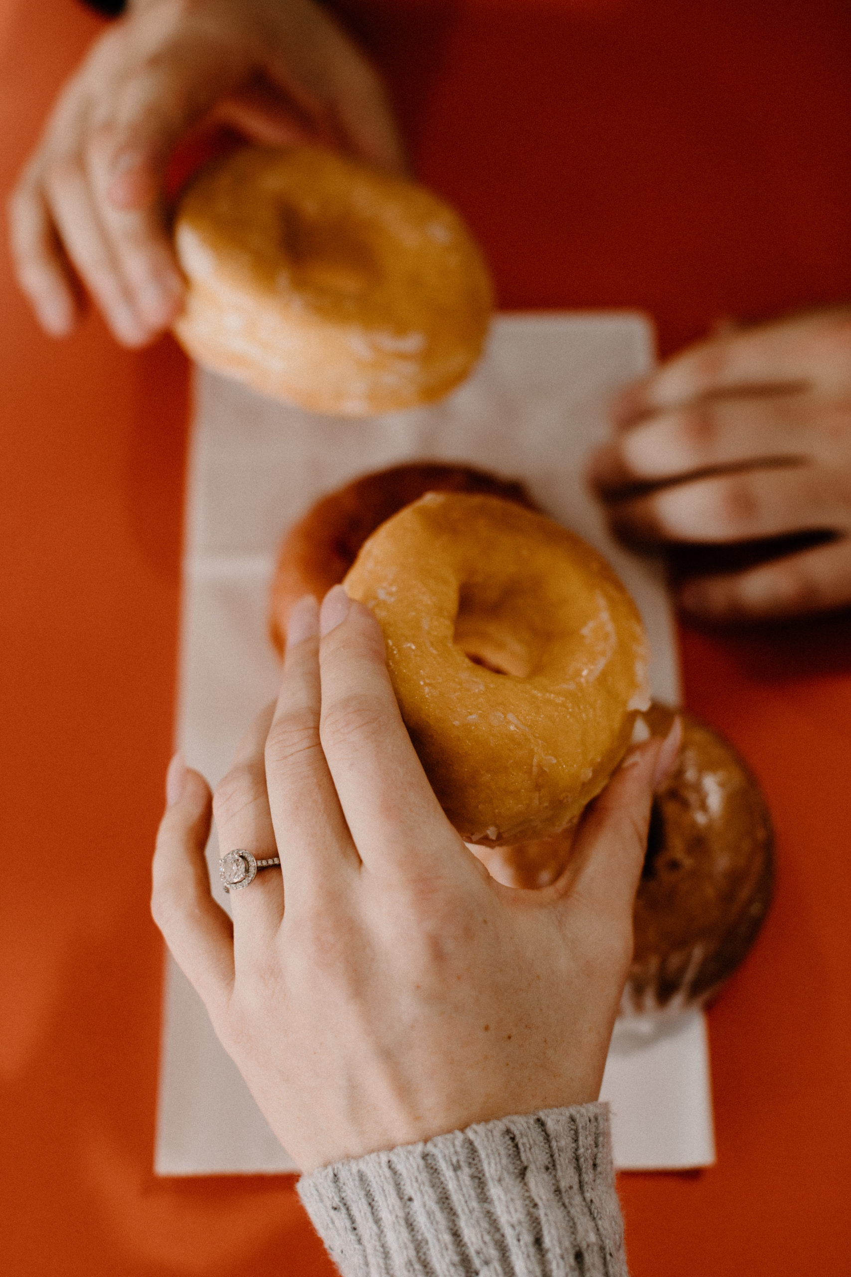 brides hand holding a donut with engagement ring on