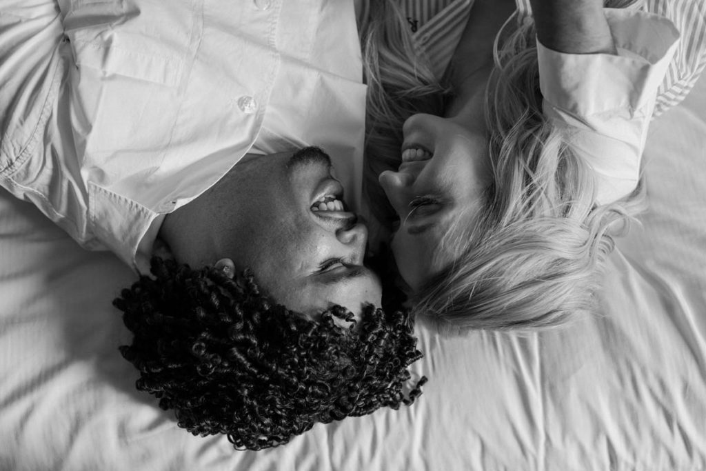 man and woman lying in bed face to face smiling