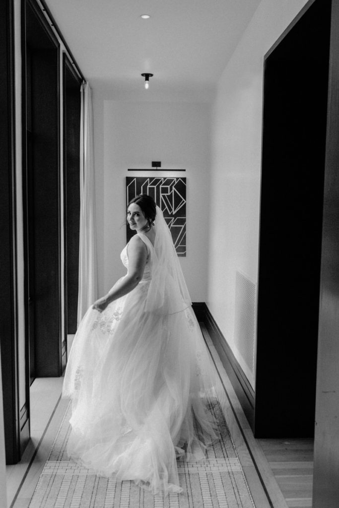 bride looking back over her shoulder as she walks down a hallway