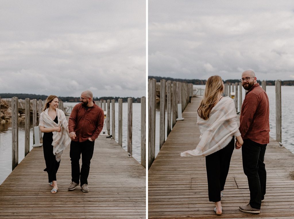 couple holding hands and smiling as they walk on a pier 