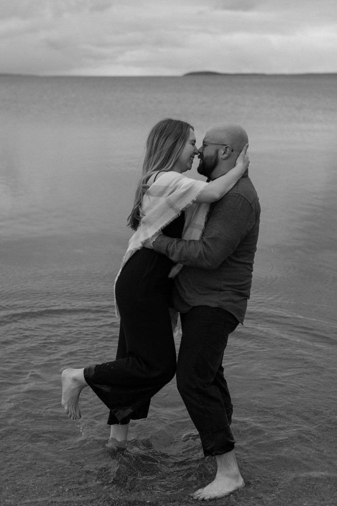 couple standing in shallow water about to kiss 