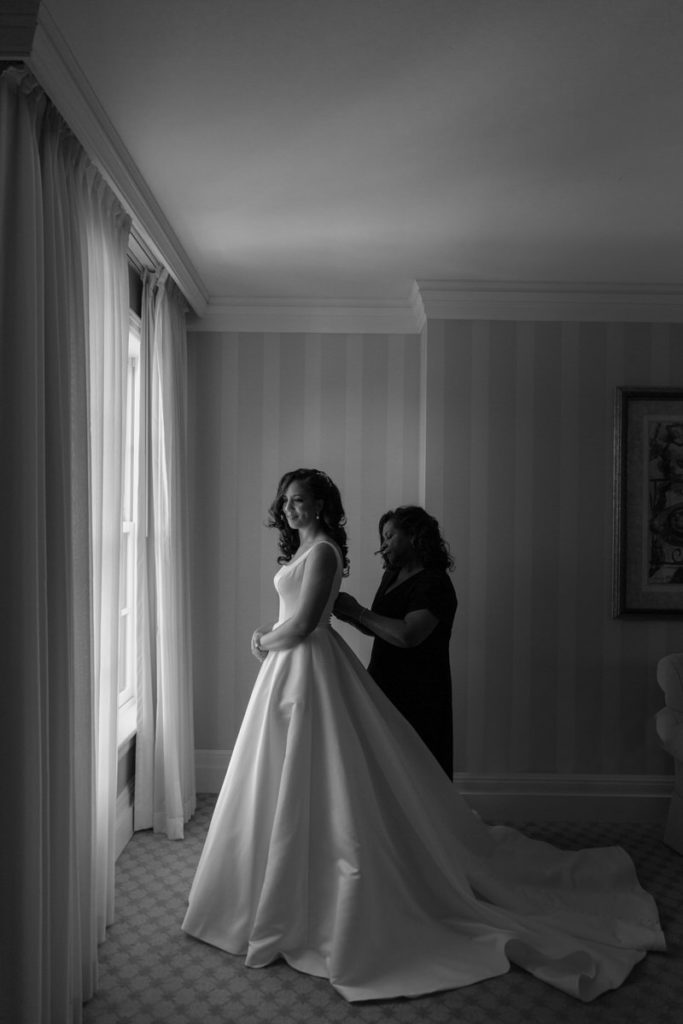 woman helping a bride zip up her dress