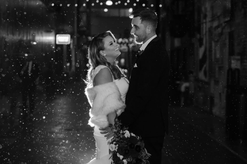 man and woman standing together in the snow on their wedding day