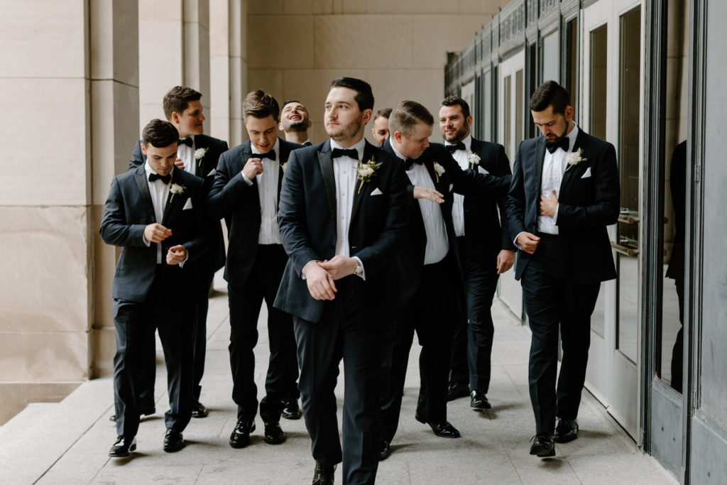 group of men in tuxes adjusting their coats and bow ties