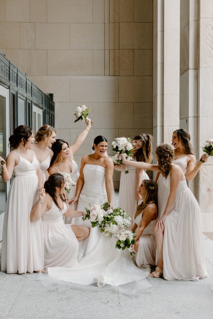 bride with bridesmaids circled around her holding bouquets of flowers