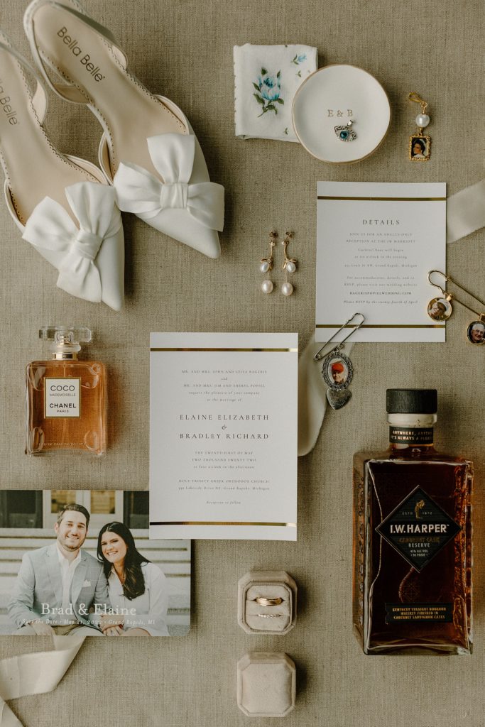 wedding invitations laid out with jewelry, shoes, and perfume around it 