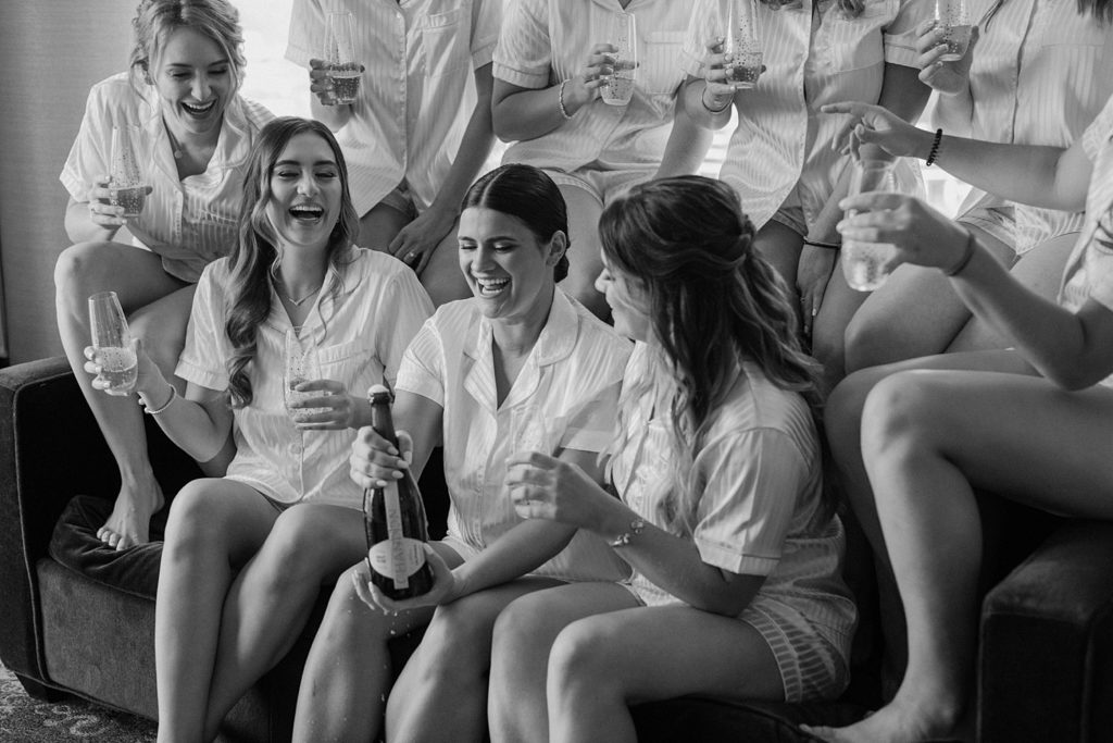 black and white photo of bride and bridesmaids drinking champagne 