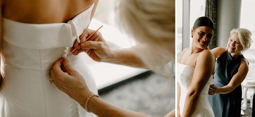 bride looking over her shoulder smiling as woman helps zip up her dress 