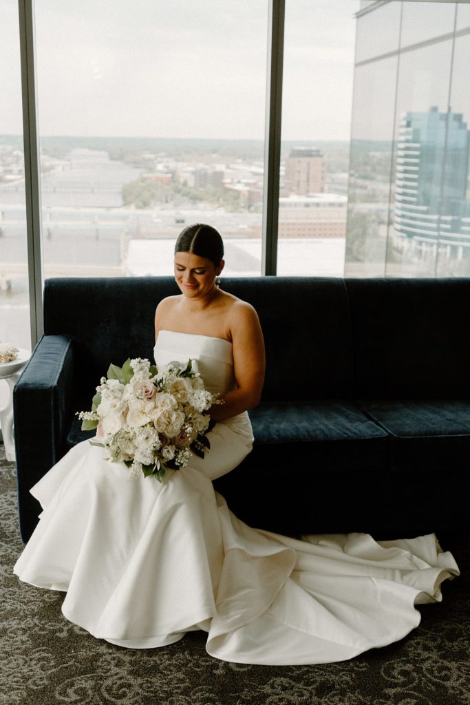 bride sitting on a couch holding a bouquet of flowers 