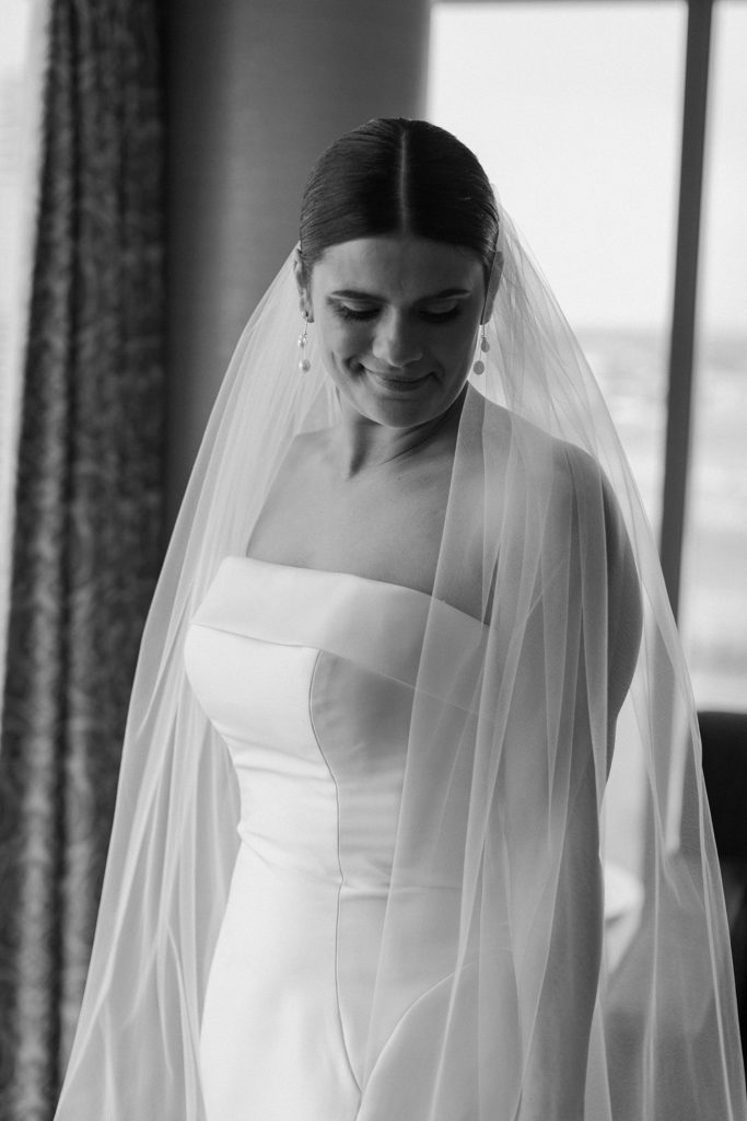 bride looking down and smiling while in her wedding dress and vail 