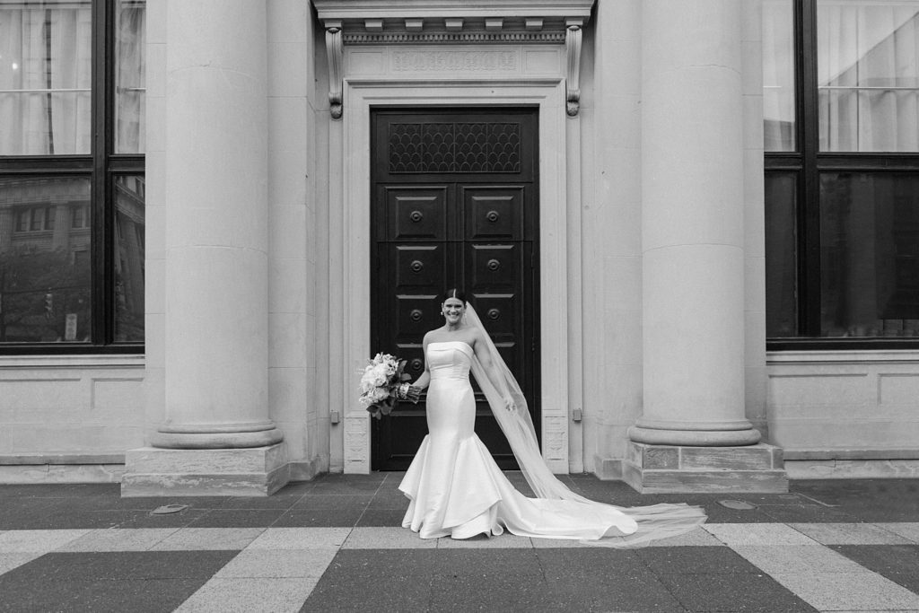 bride standing in front of a large door smiling 