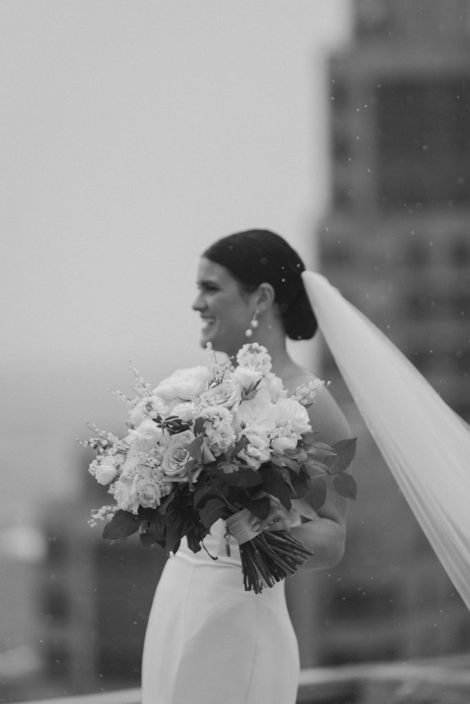 bride holding bouquet of flowers as it rains slightly 