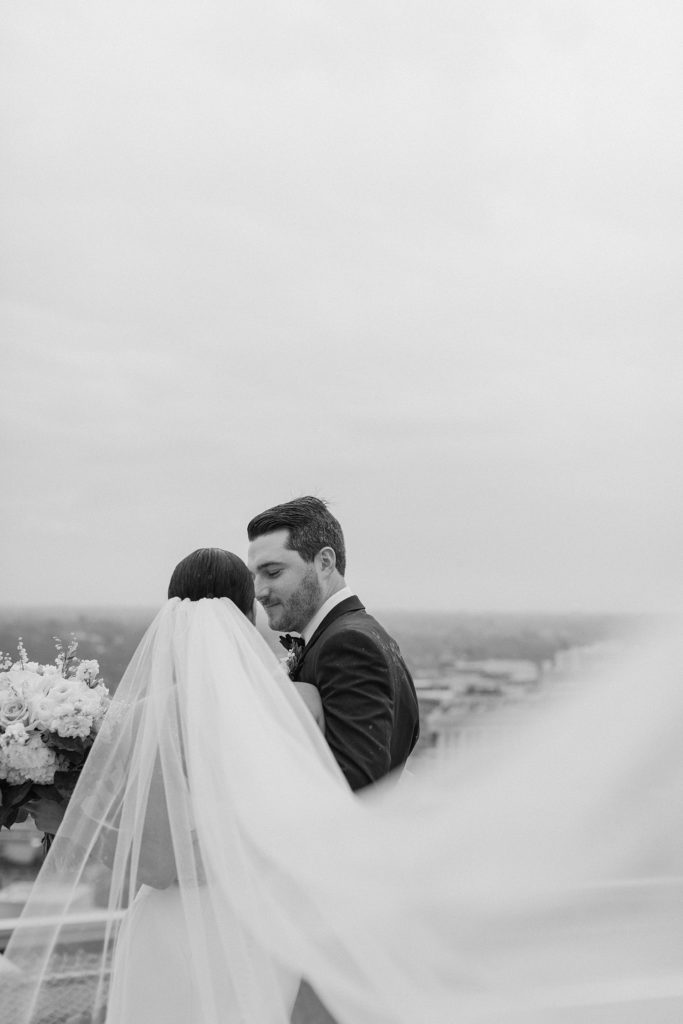 bride and groom kissing while her vail flying in the wind 
