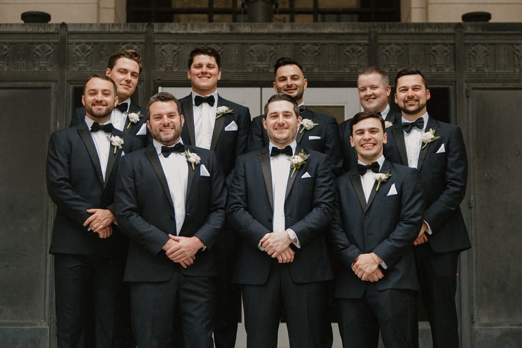 groom and wedding party smiling and standing together 