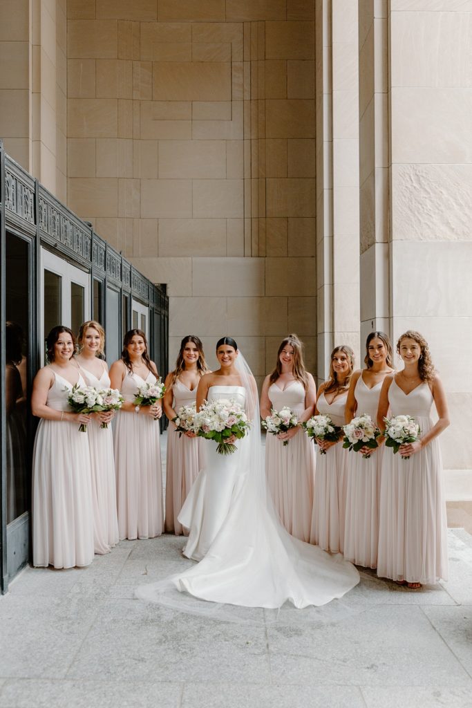 bride standing in the middle of all of her bridesmaids smiling 