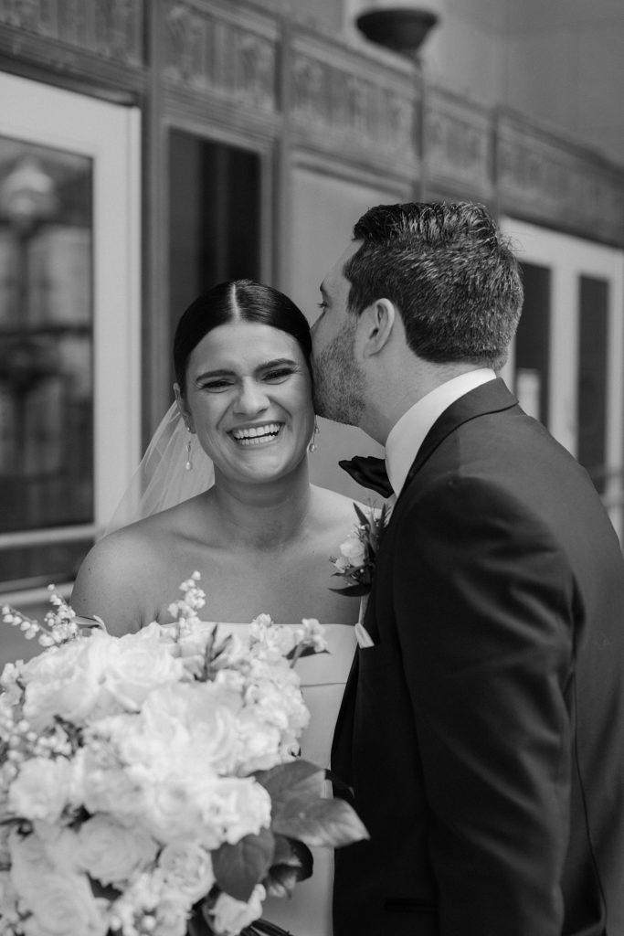 bride smiling as groom kisses her head 