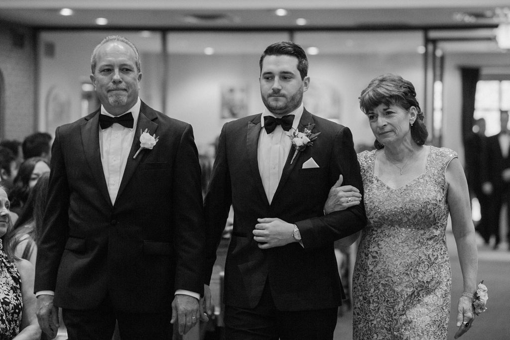 groom walking down the aisle with his parents 