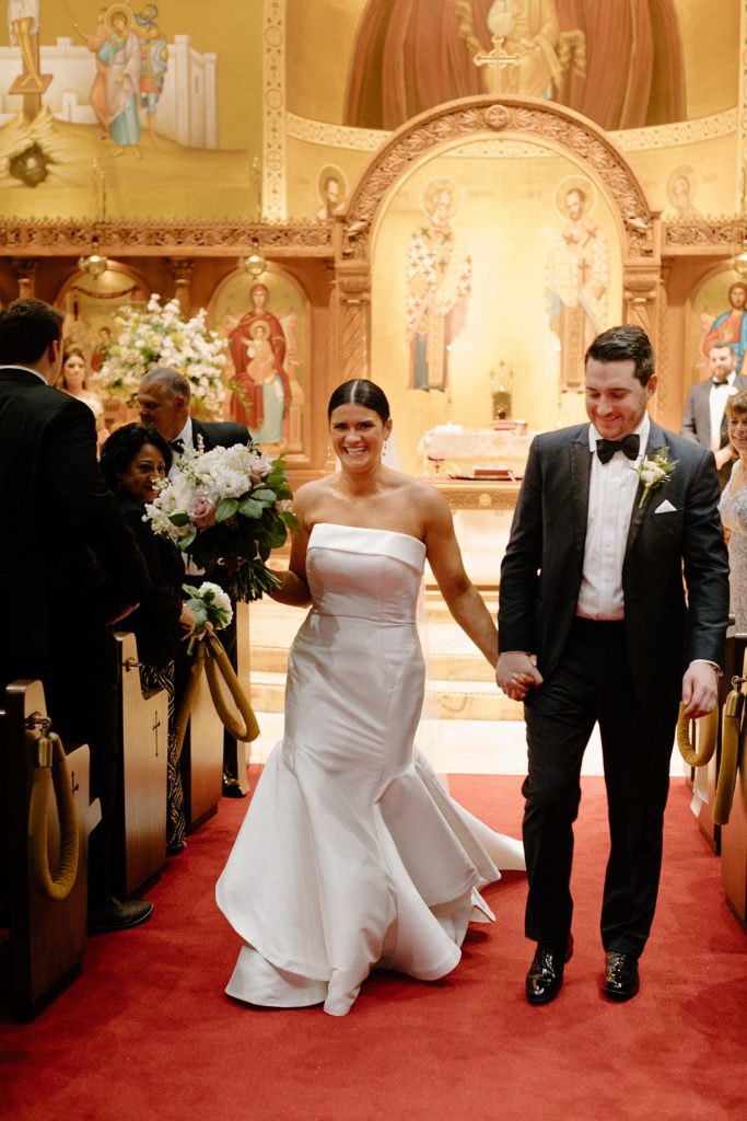 couple holding hands and walking back up the aisle 