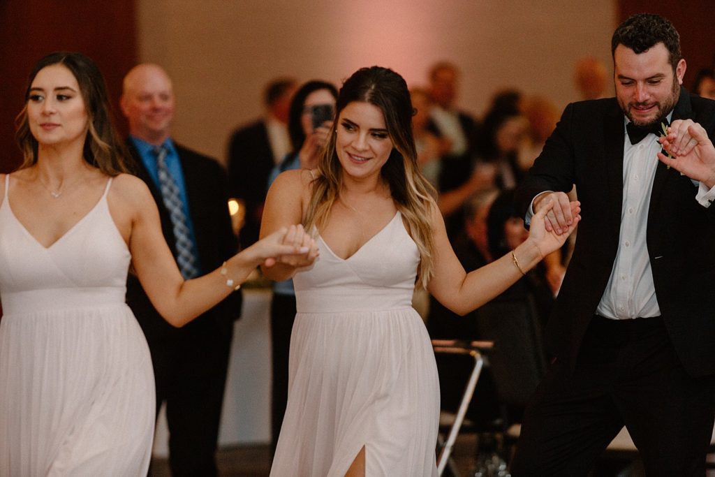 line of wedding guests holding hands and dancing 
