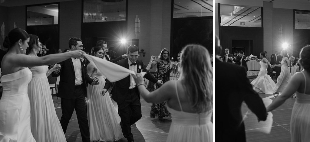 black and white photo of wedding guests holding hands and dancing 