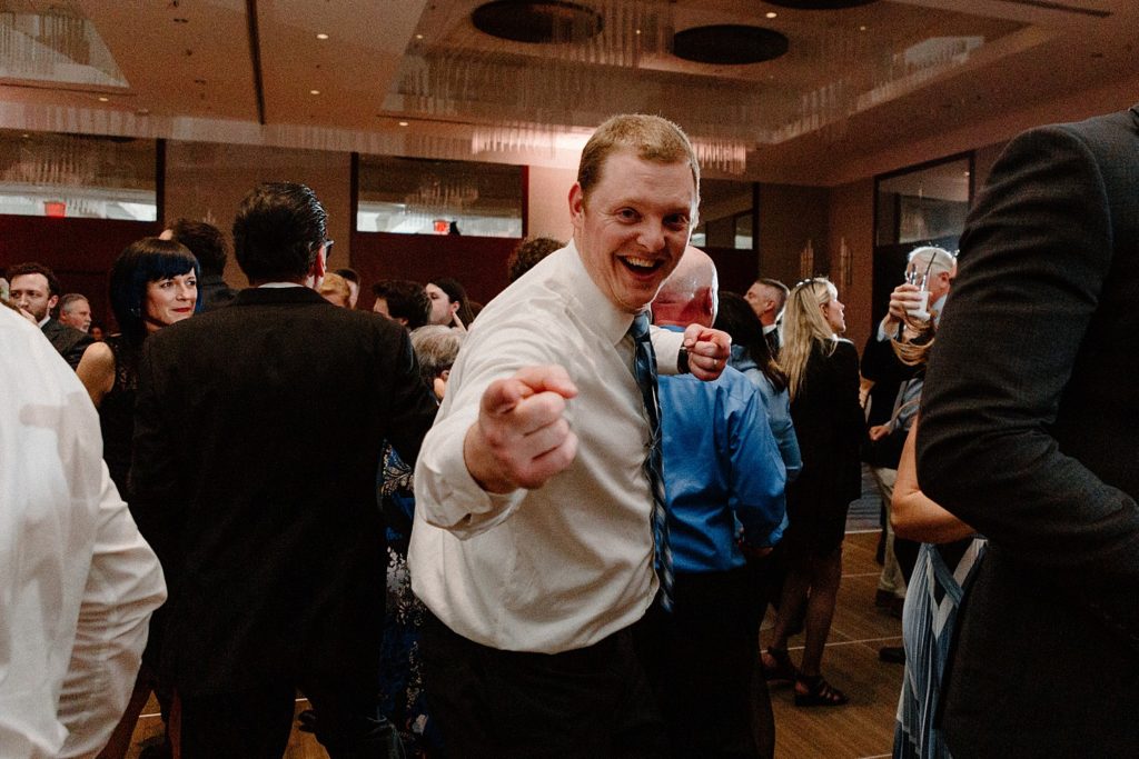 guest smiling and pointing at the camera on the dance floor 
