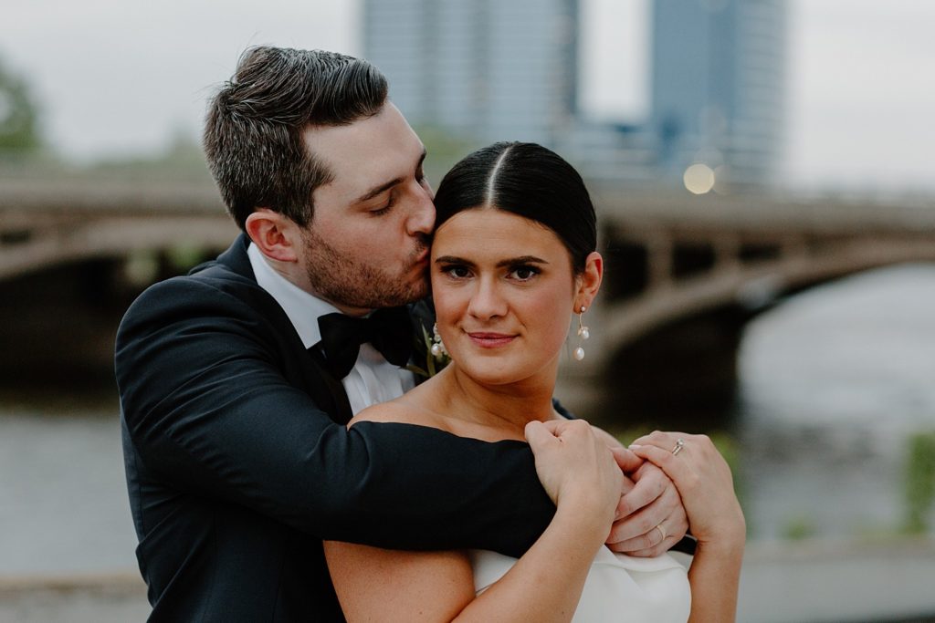 man hugging his bride from behind and kissing her head 