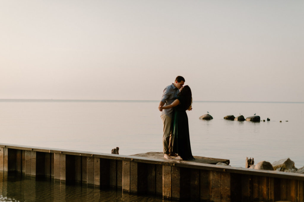 couple kissing while standing on a pier
