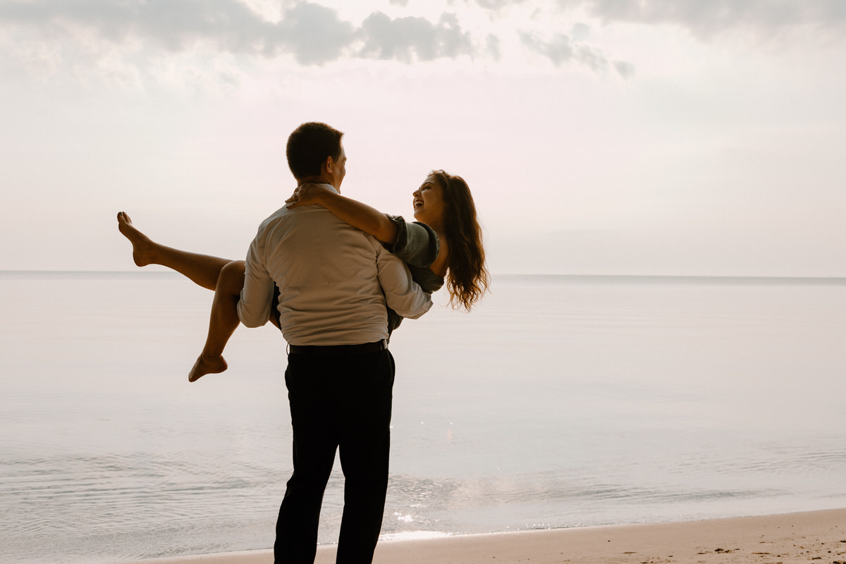 man holding a woman on the beach