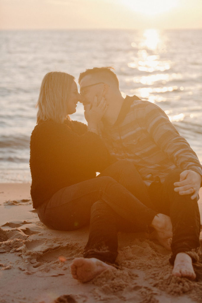 couple sitting on the beach about to kiss at sunset