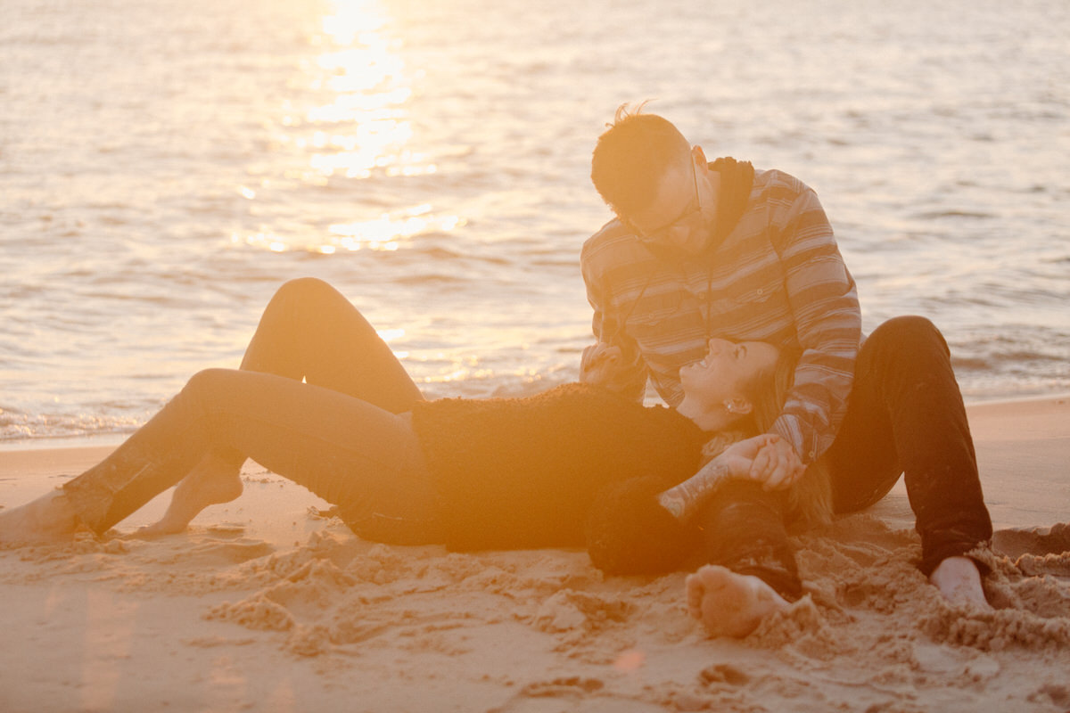 man sitting on the beach with woman laying down on his lap at sunset 