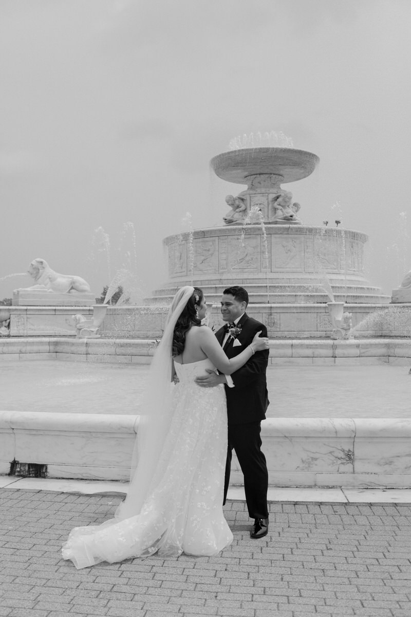 wedding couple standing in front of large fountain 