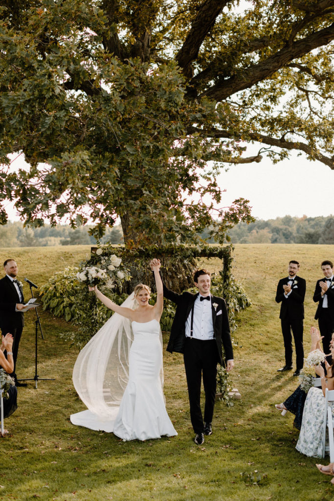 couple walking with their arms raised after saying vows