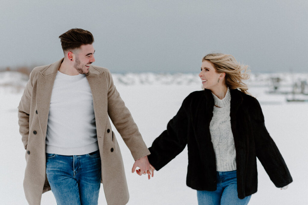 Couple holding hands and looking at each other as they walk along the snow