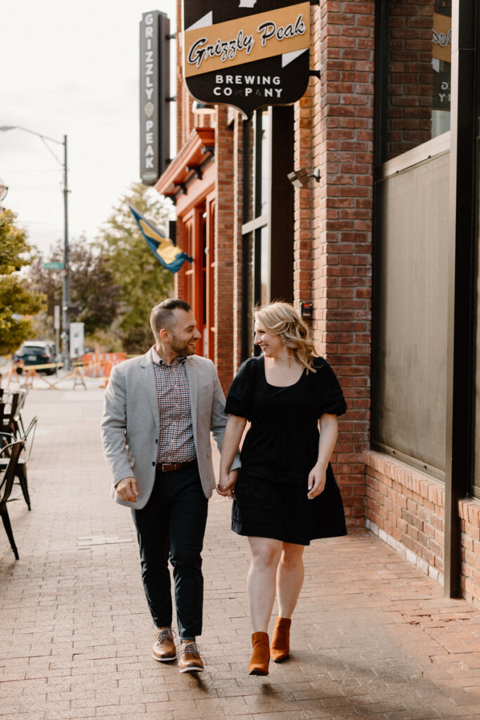 couple walking along the sidewalk in a town while they are holding hands
