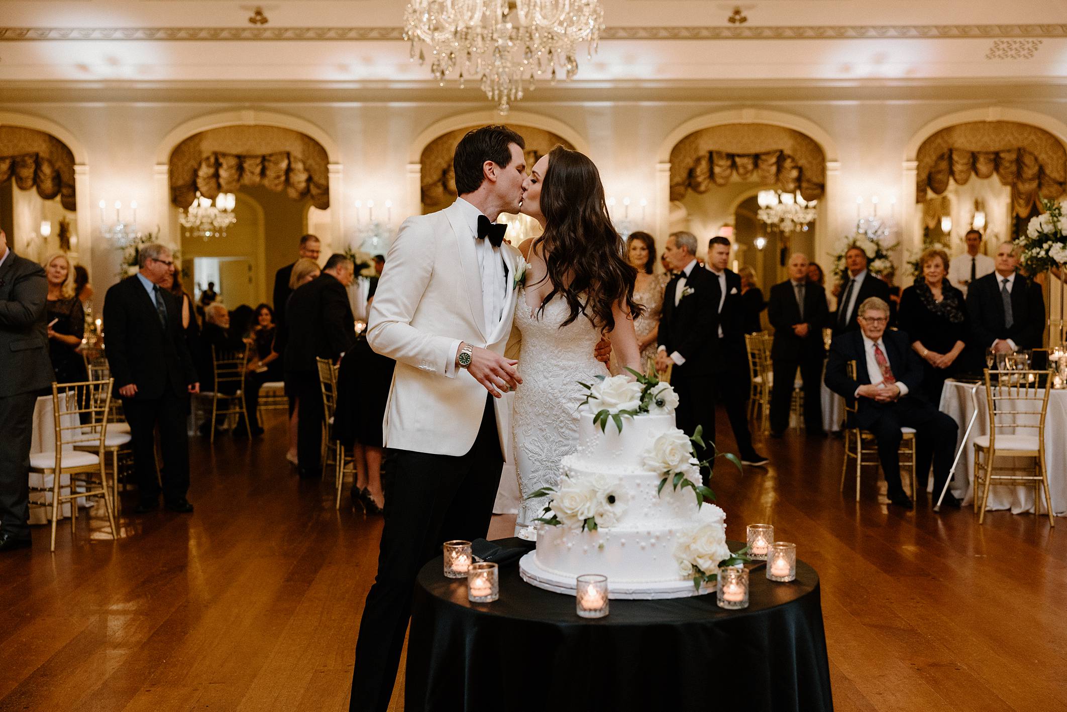 bride and groom kissing after cutting wedding cake in lovett hall's ballroom